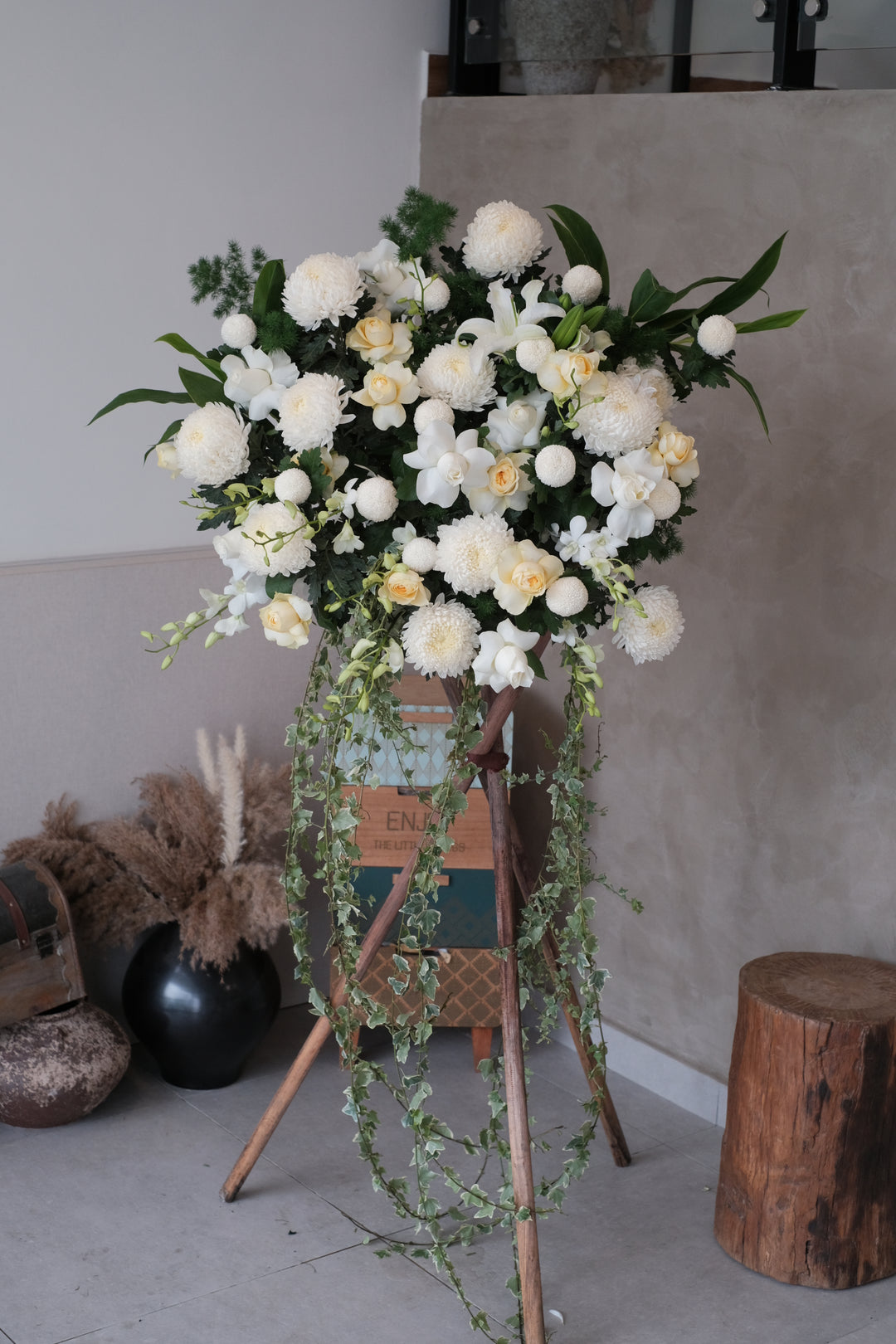 Delicate the full and abundant life of your loved one with this profusion of white chrysanthemums, lilies, roses, orchids surrounded by leaves. For same day condolences flowers delivery in Penang.  