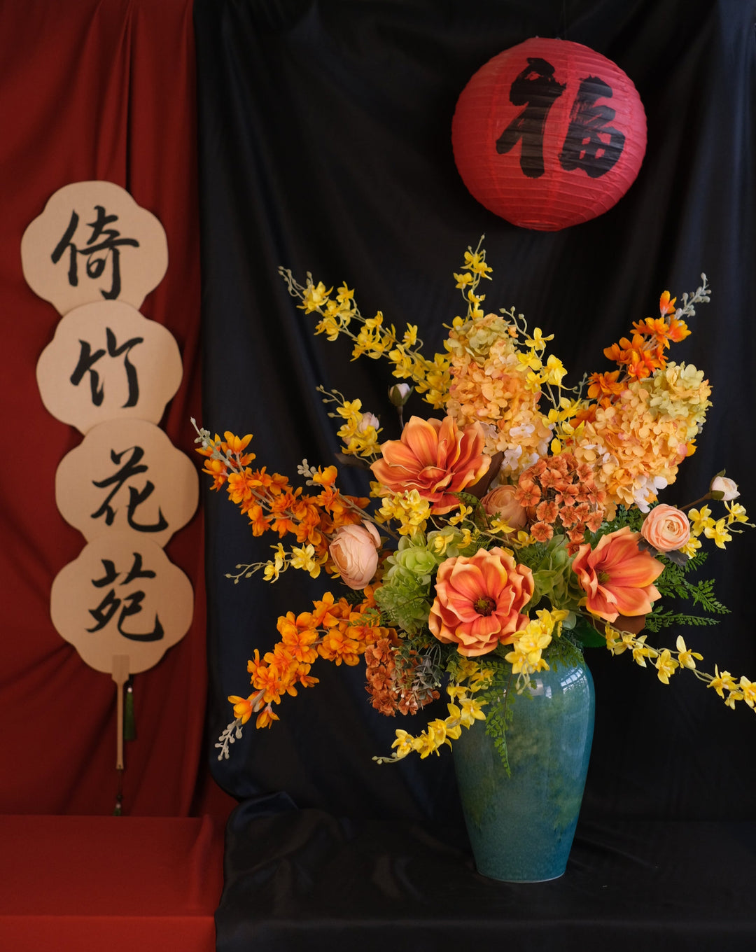 Elegant Chinese New Year floral arrangement featuring vibrant red blooms with purple accents in a red ceramic painted pot, showcasing an oriental design and festive charm.