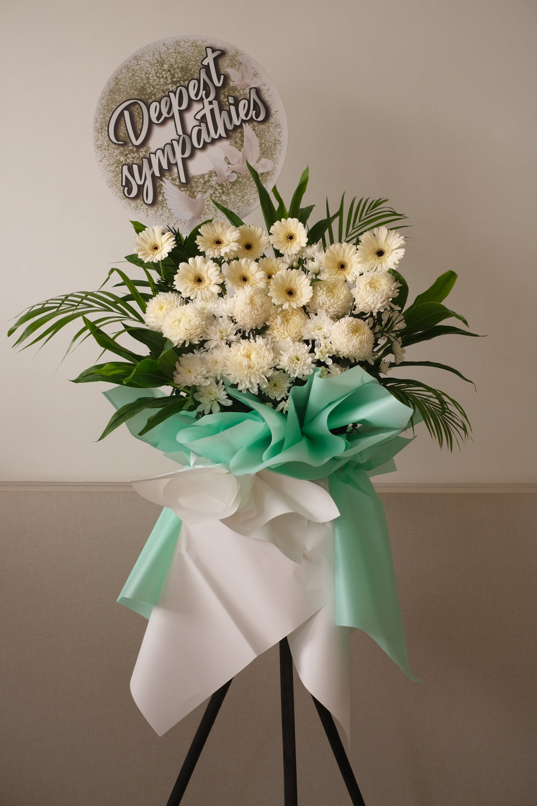 Delicate the full and abundant life of your loved one with this profusion of white chrysanthemums,  white gerberas and poms surrounded by leaves.