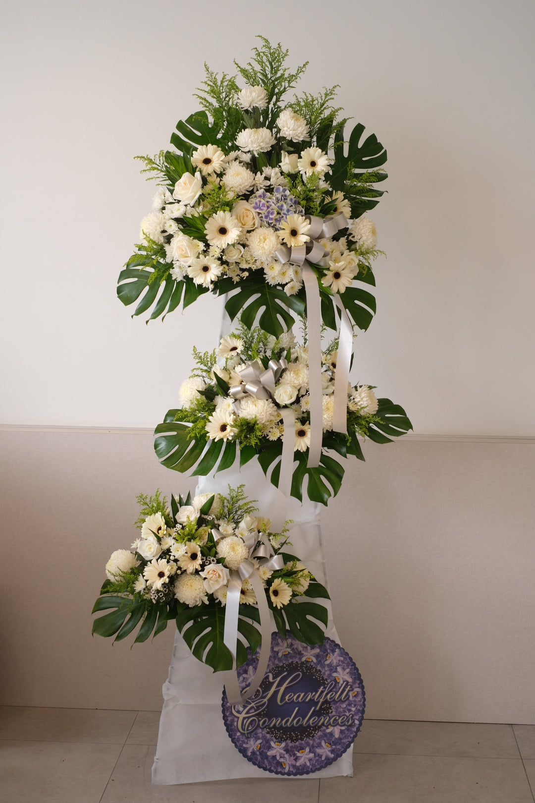 Comprises 3 layers of condolences wreath with ornamental cabbage, gerberas, chrysanthemums, white roses and poms poms. For same day condolences flowers delivery in Penang.