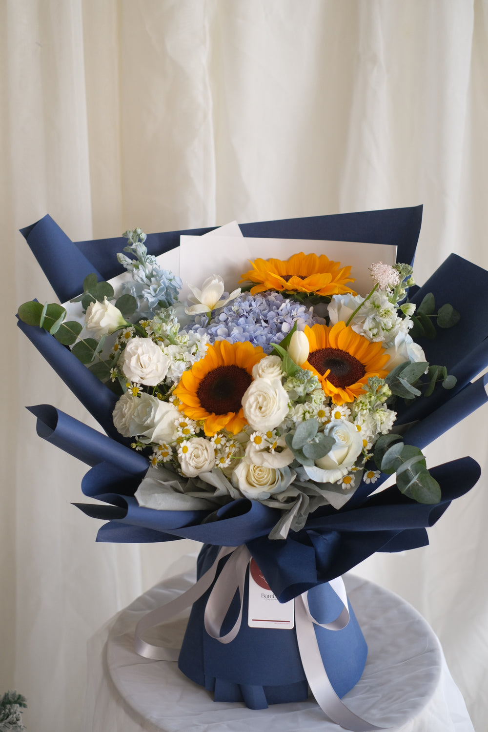 Dream Chaser fresh flowers graduation bouquet by Penang florist Bamboo Green – featuring blue hydrangeas, blue roses, and chamomile. Trusted florist brand online for 40 years.