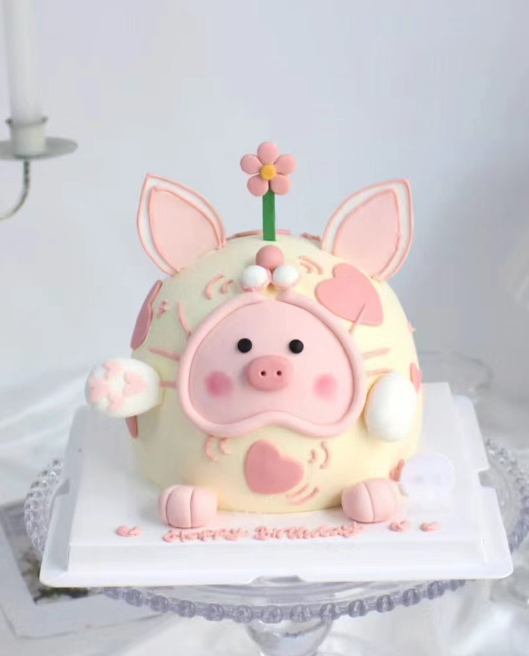An adorable, customized Lulu Pig fondant cake made in Penang, featuring a pink piglet with big eyes, a sweet smile, tiny ears, and a curly tail. The pig sits on a grassy fondant base, bringing a playful, farm-themed vibe. The cake has multiple layers inside, making it both delightful and delicious—perfect for special celebrations in Penang