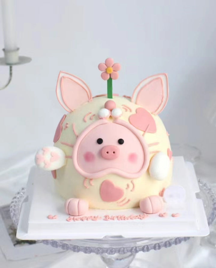 An adorable, customized Lulu Pig fondant cake made in Penang, featuring a pink piglet with big eyes, a sweet smile, tiny ears, and a curly tail. The pig sits on a grassy fondant base, bringing a playful, farm-themed vibe. The cake has multiple layers inside, making it both delightful and delicious—perfect for special celebrations in Penang