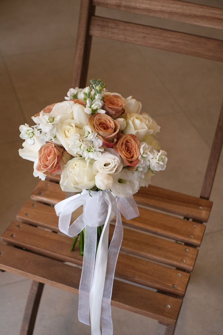 A stunning bridal bouquet by Penang Florist, featuring a blend of cappuccino and white roses, accented with soft greenery for a timeless and elegant look.