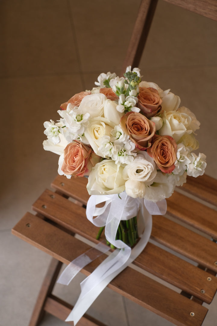 A stunning bridal bouquet by Penang Florist, featuring a blend of cappuccino and white roses, accented with soft greenery for a timeless and elegant look.