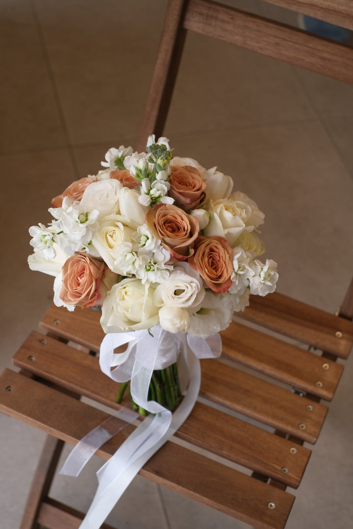 A stunning bridal bouquet by Penang Florist, featuring a blend of cappuccino and white roses, accented with soft greenery for a timeless and elegant look.