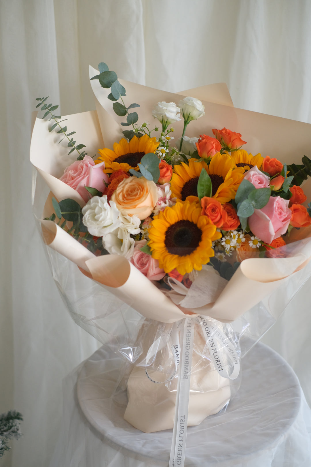 Next Chapter Blooms bouquet by Penang florist Bamboo Green – featuring pink and orange roses with sunflowers, perfect for a sweet lady.