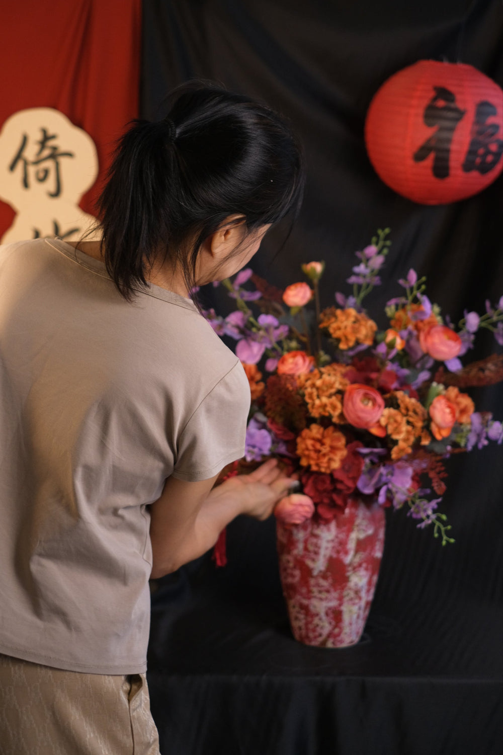 Elegant Chinese New Year floral arrangement featuring vibrant red blooms with purple accents in a red ceramic painted pot, showcasing an oriental design and festive charm.