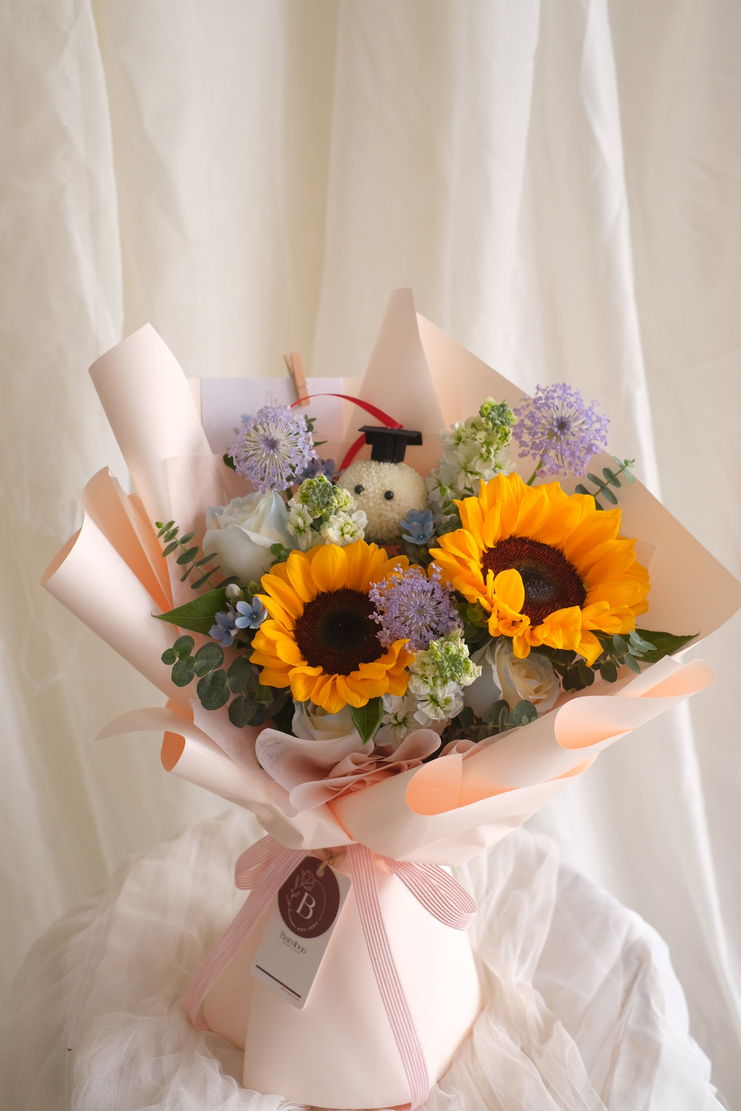 Soar High Bouquet – 2 sunflowers, roses & playful ping pong graduates icons. Celebrate her success with this vibrant arrangement. Penang florist, Order online, deliver same day, graduation.