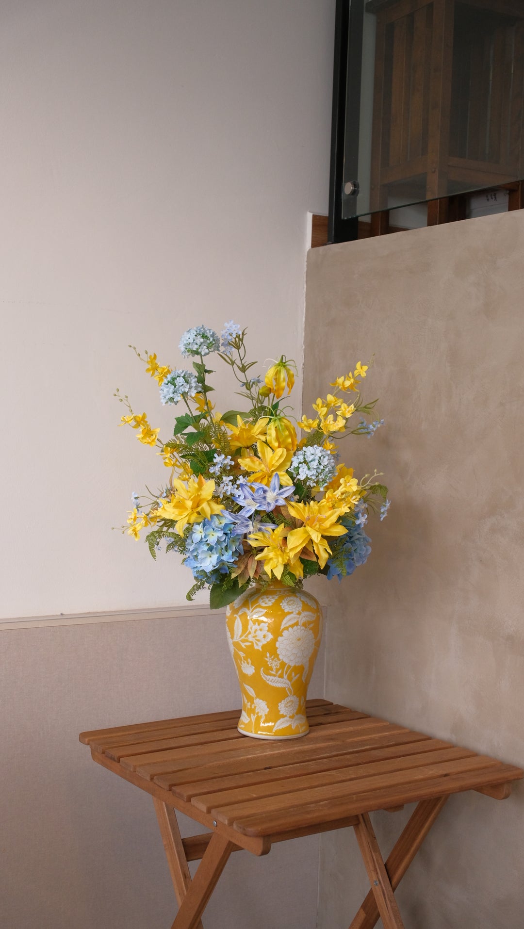 Maison Flor artificial flower arrangement with yellow lilies, glory lilies, and blue snowballs in a hand-finished yellow ceramic designer vase.