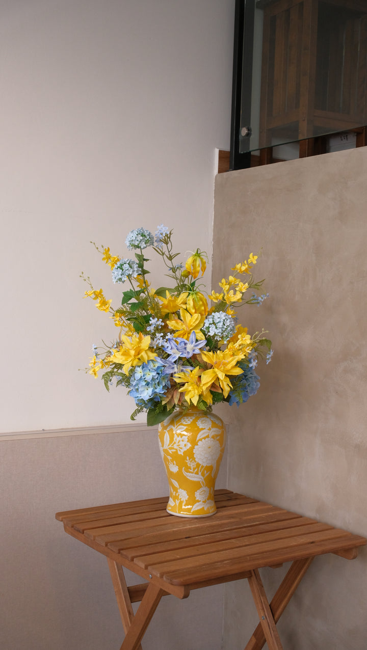 Maison Flor artificial flower arrangement with yellow lilies, glory lilies, and blue snowballs in a hand-finished yellow ceramic designer vase.