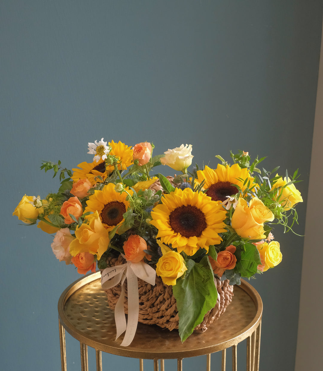 A stunning floral arrangement featuring sunflowers, yellow and orange roses, eustomas, seasonal fillers, and lush leaves. Perfect for any occasion. Same-day delivery available with Penang florist Bamboo Green Florist.
