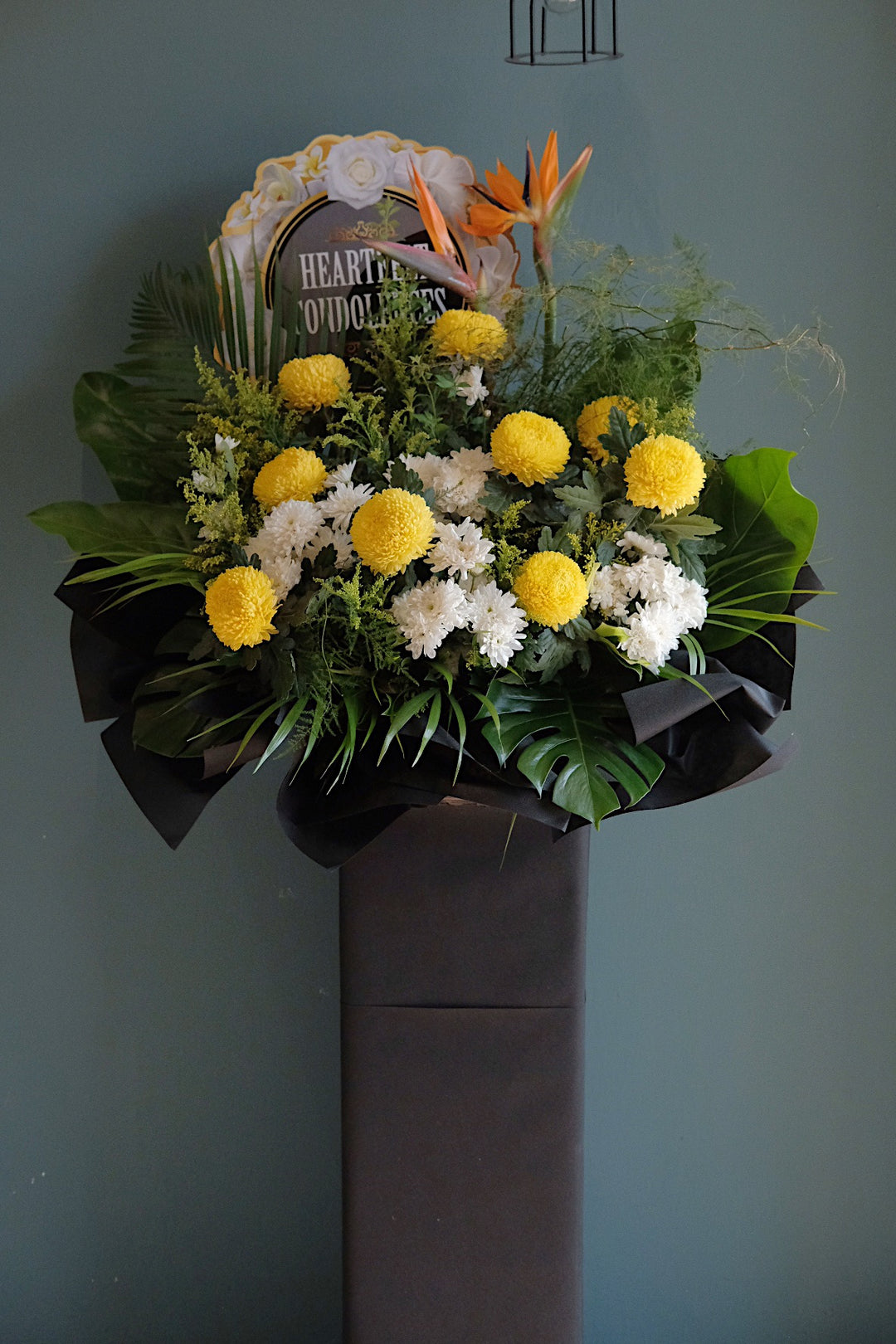 This beautiful, yellow Chrysanthemums, Bird of Paradise and soothing greens creates a peaceful presentation at any funeral or wake.   Note: Florals used and final design will vary depending on seasonality and availability.  For same day condolences flowers delivery in Butterworth