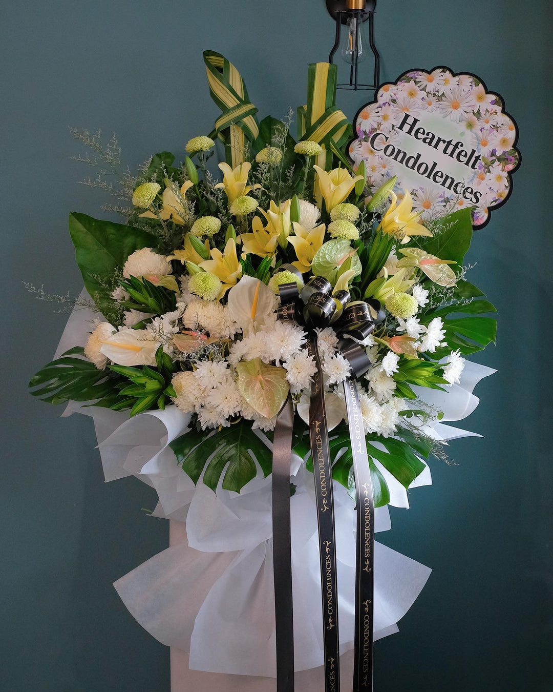 Through this yellow lilies, ping pongs, anthuriums, white chrysanthemums , greens, to remember the great life of the love. For same day condolences flowers delivery in Penang.