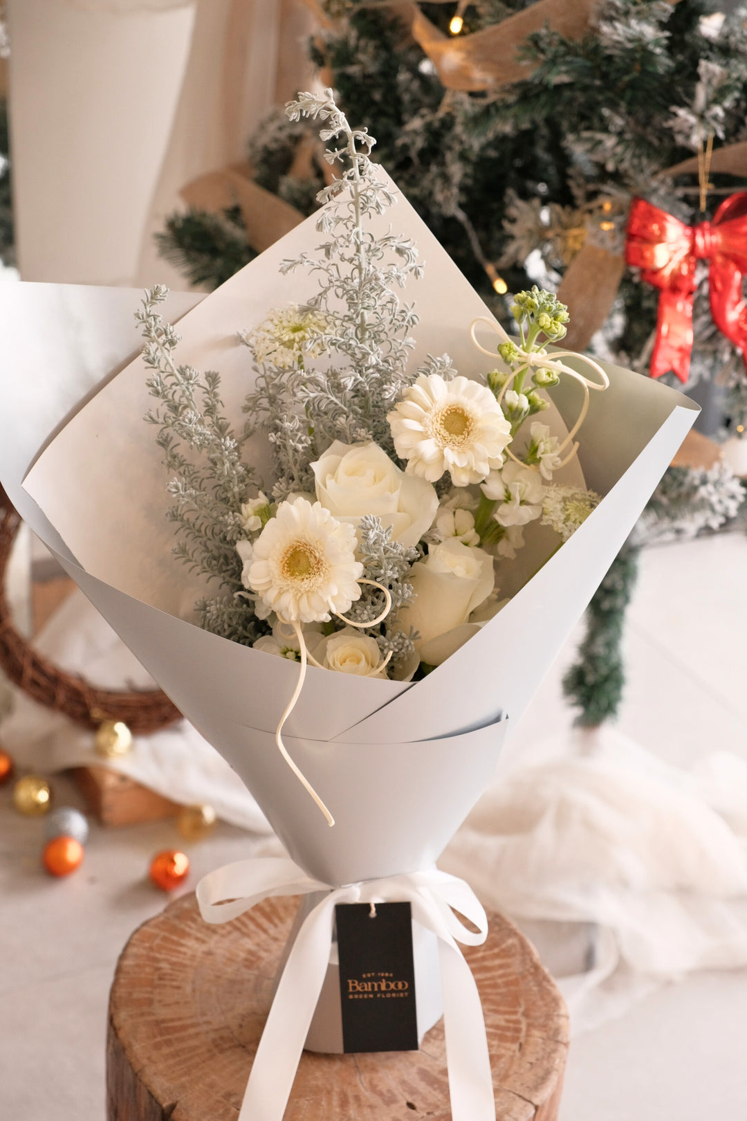 Snowlight bouquet featuring white roses, white gerberas and silvery foliage wrapped in elegant soft grey paper
