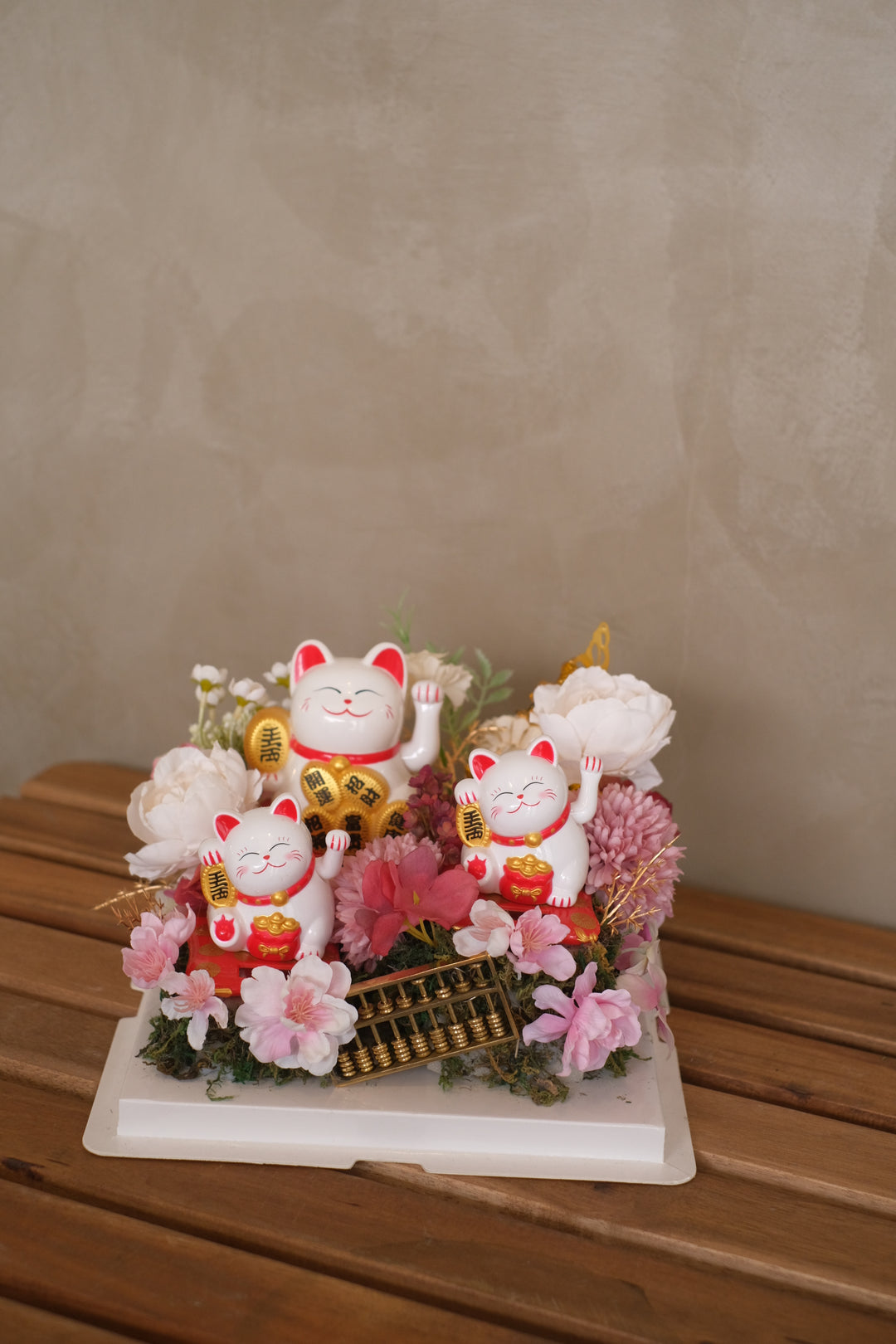 Lucky cats, also known as Maneki-neko, are believed to bring good luck and prosperity. Combining them with artificial flowers symbolizes a wish for success and positive outcomes in the new venture.