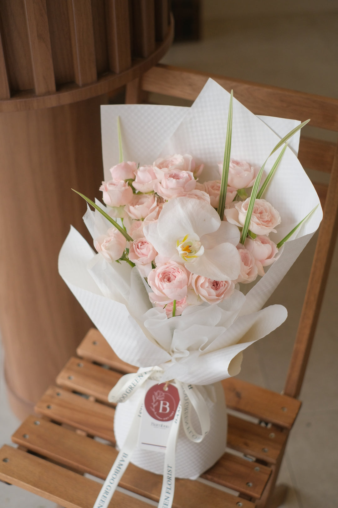 Elegant pink spray roses paired with a single pristine Phalaenopsis orchid for a delicate, sophisticated touch. Order online from Bamboo Green Florist, your trusted Penang florist with delivery.