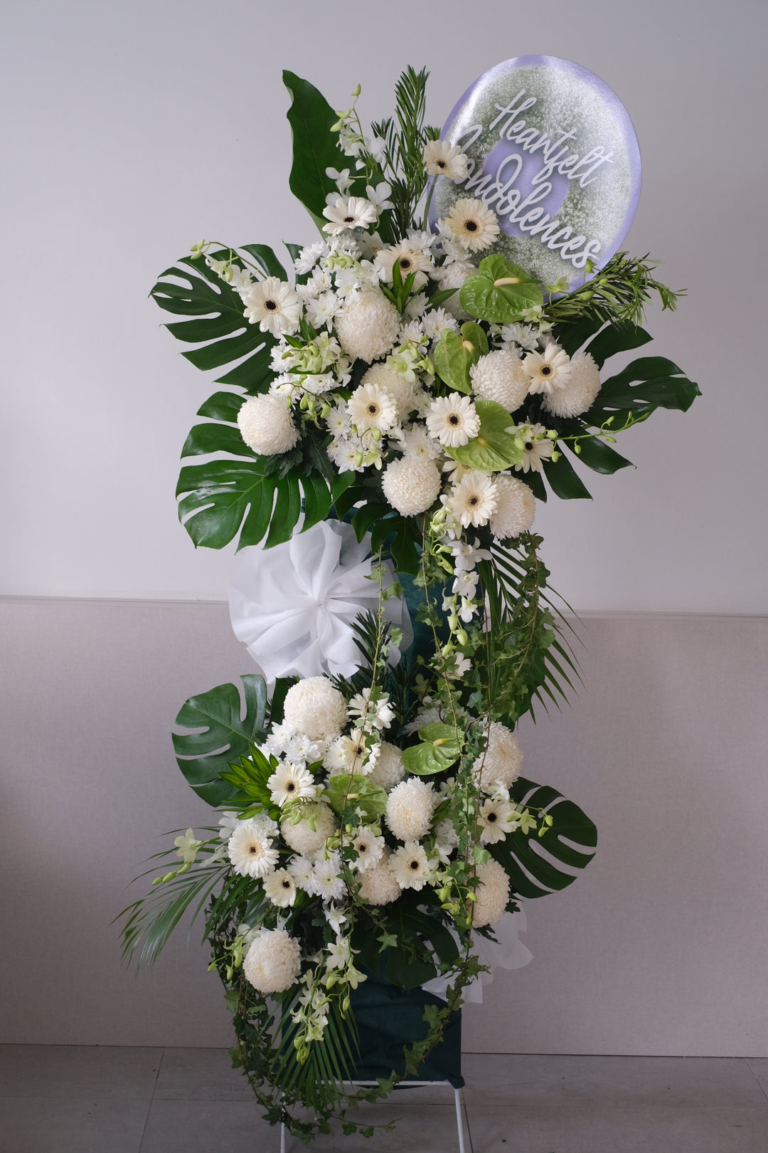 Let the family members know you care and understand with a simple gesture with the condolences stand comprises with white chrysanthemums, ping pongs, anthuriums, daisies, golden showers and lush leaves. For same day condolences flowers delivery in Penang.