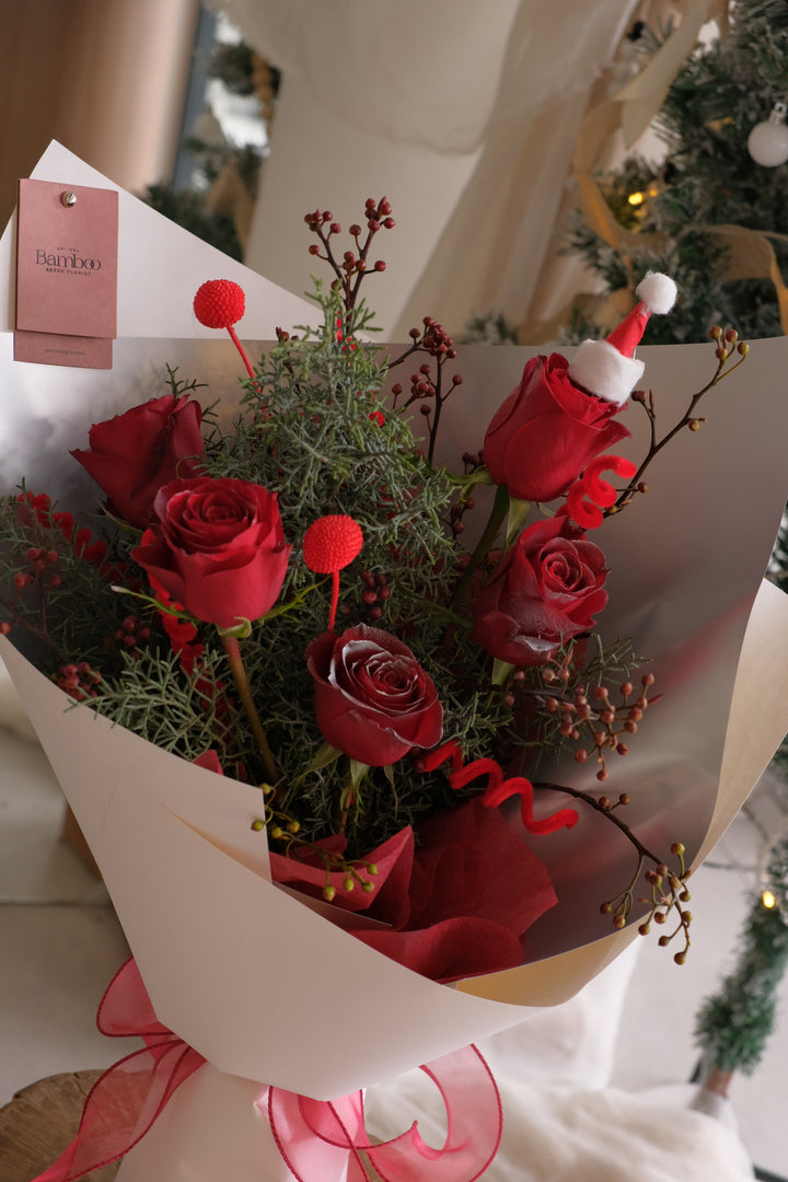 Red rose Christmas bouquet with festive greenery