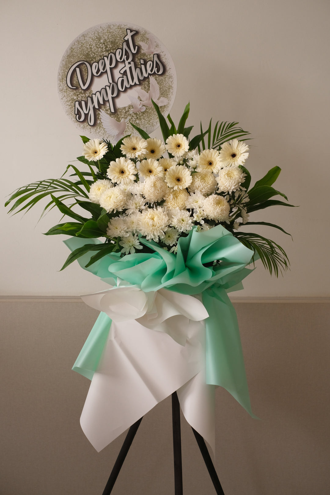 Delicate the full and abundant life of your loved one with this profusion of white chrysanthemums,&nbsp; white gerberas and poms surrounded by leaves.