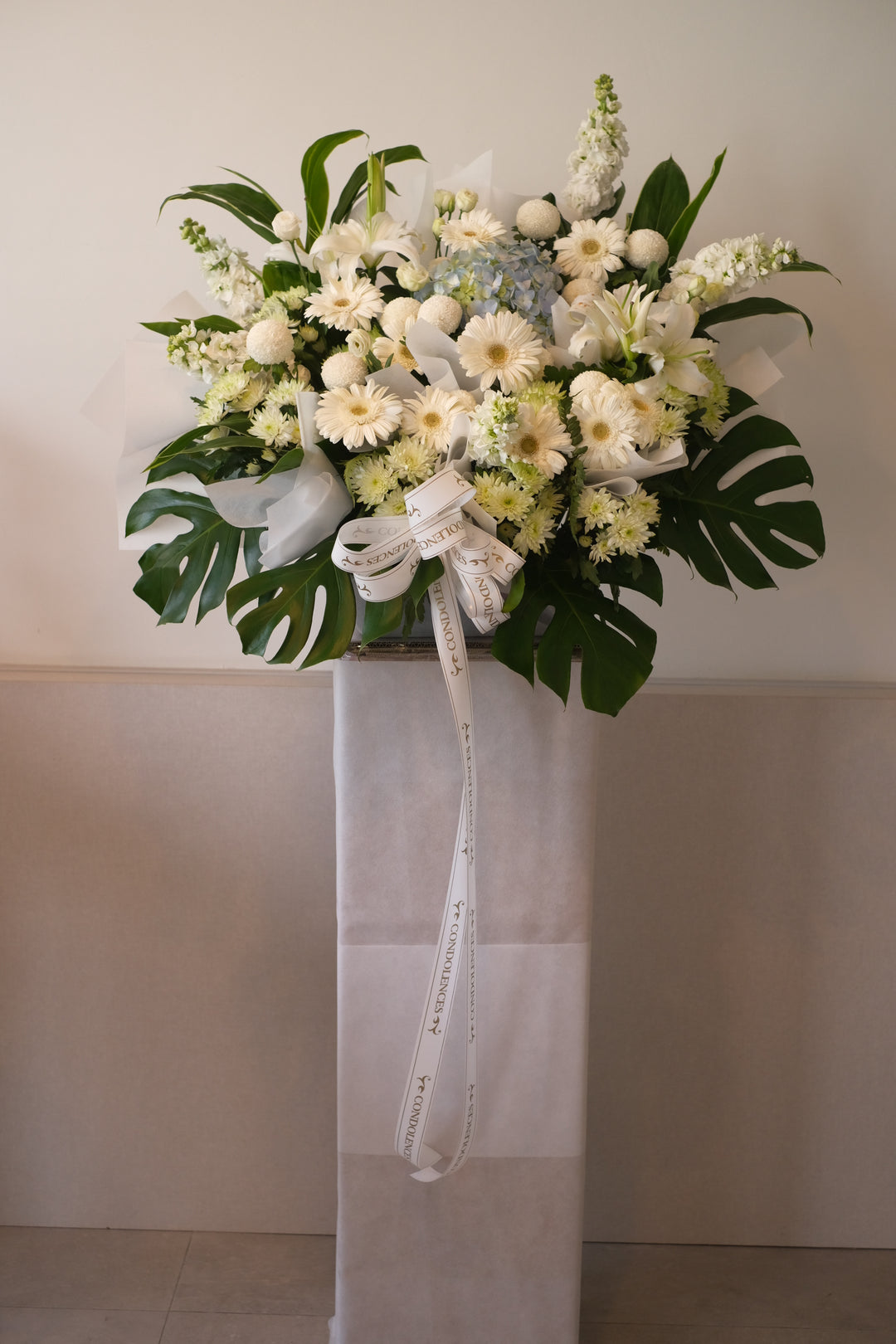 hydrangea flowers and daisies on a white stand for funeral occasions