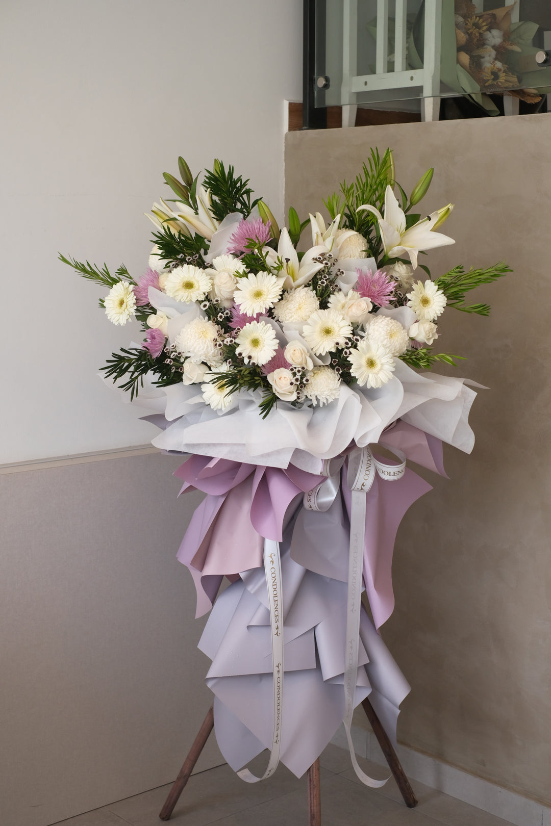 <span>Blessed, peaceful rest is expressed in this condolences stand</span><span>&nbsp;comprises with white rose, white daisies, chrysanthemums, white liles, ping pongs and lush leaves.</span>