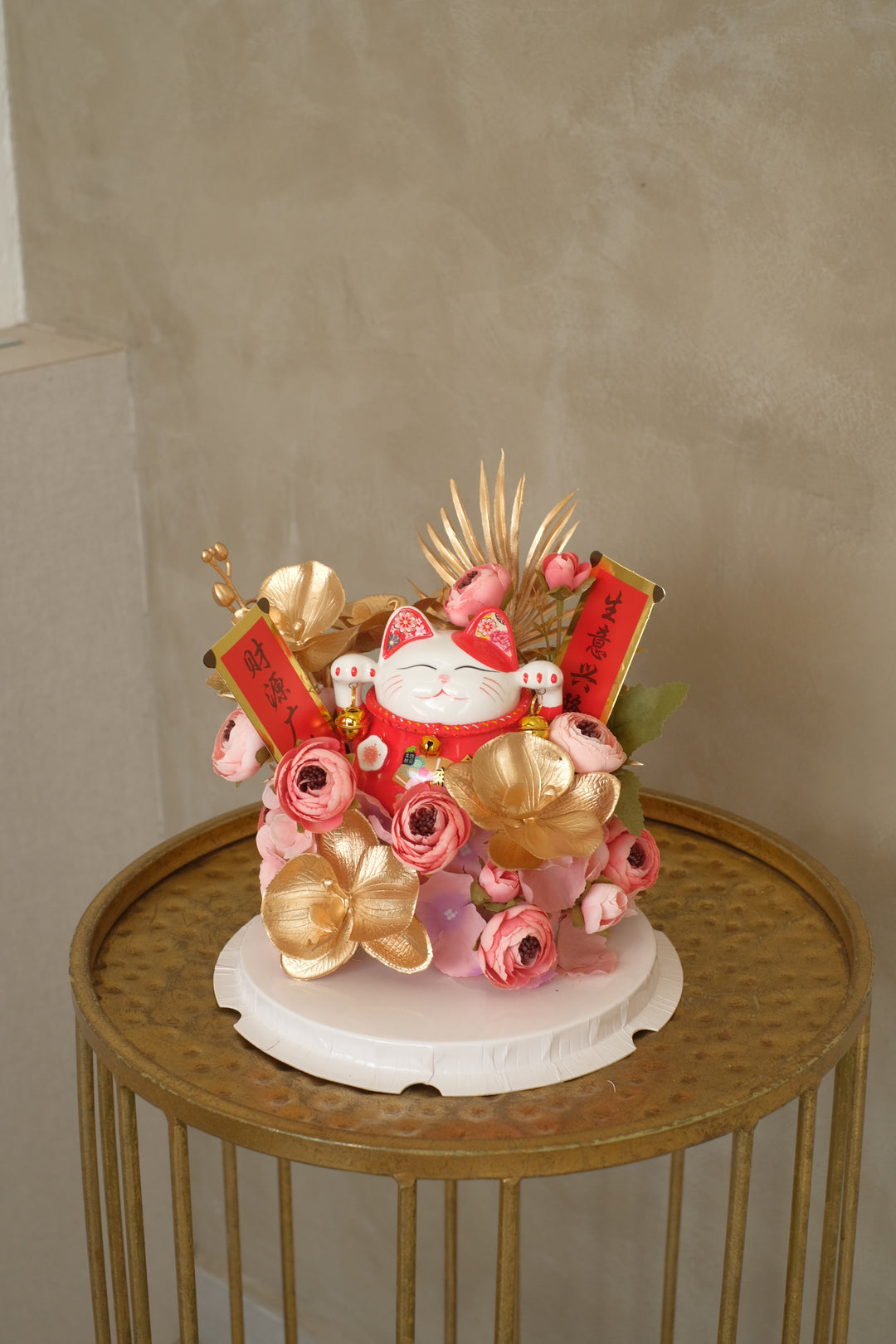 A compact clear box arrangement featuring a Lucky Cat figure surrounded by vibrant orange and red artificial flowers, symbolizing prosperity and good luck.