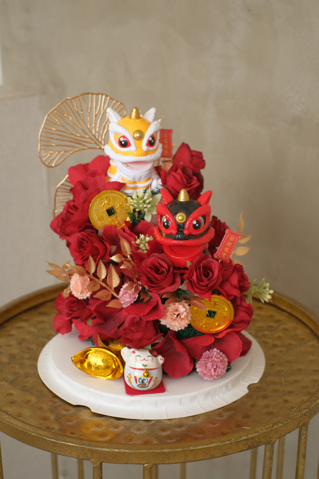 A bold floral arrangement in a clear box featuring a traditional dancing lion figure, surrounded by orange and red artificial blooms symbolising luck, protection, and new beginnings.


