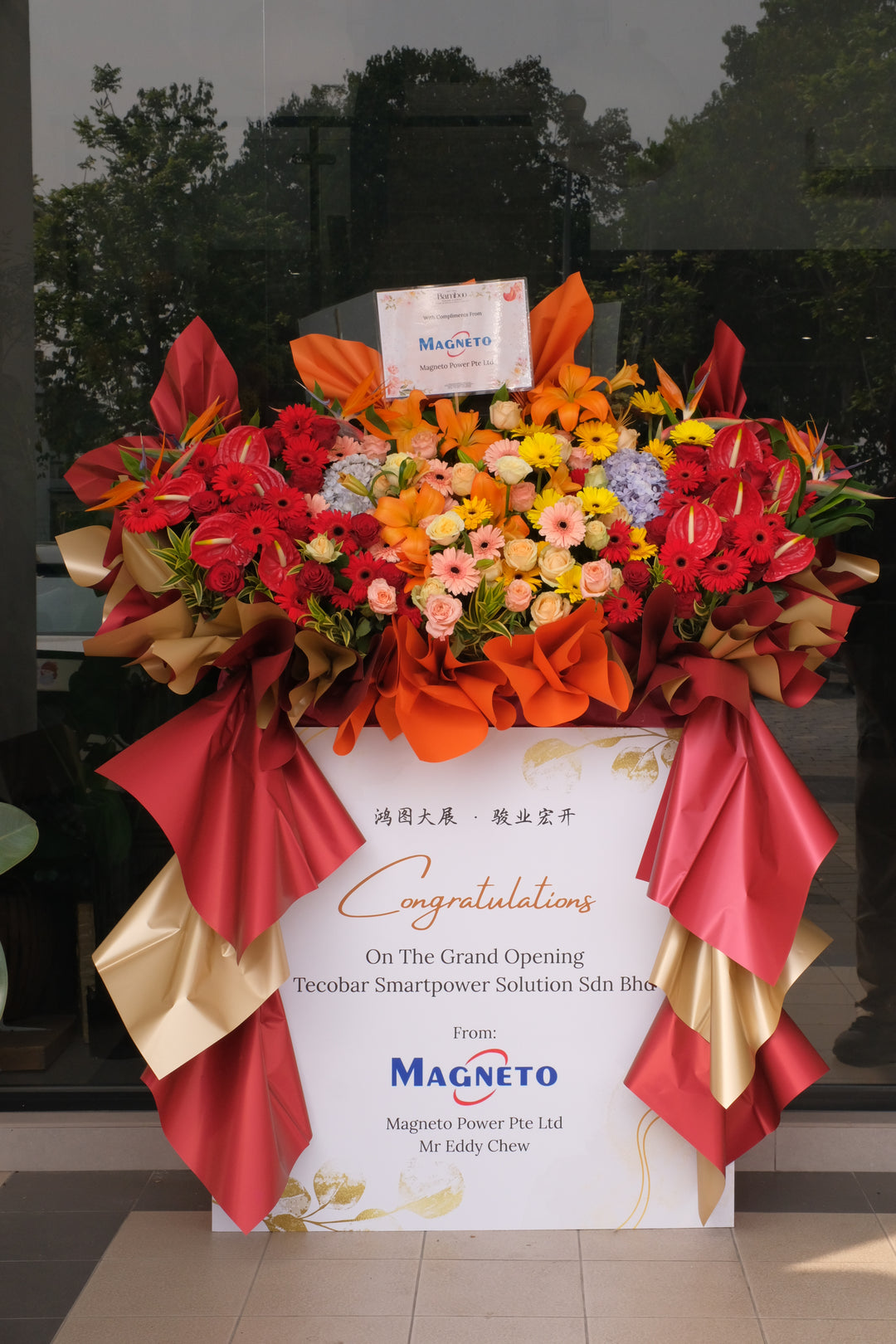 Large congratulatory flower stand for business grand opening in Penang, featuring vibrant tropical blooms and personalised printed card by Bamboo Green Florist

