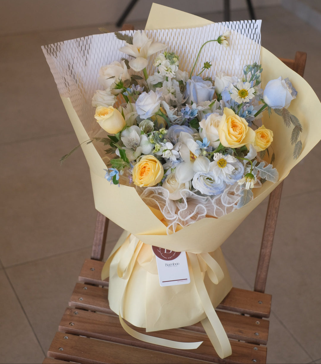 A dreamy pastel bouquet bursting with soft pinks, creamy whites, and lush greens, accented by striking blue blooms for contrast. Handcrafted by a Penang florist with fresh flowers, delicate bamboo accents, and wrapped in eco-friendly green packaging—perfect for same-day delivery!"