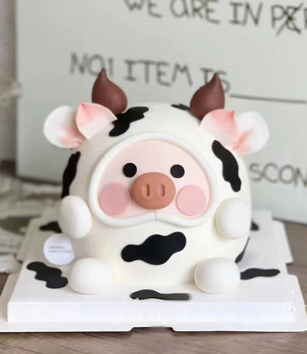 An adorable, customized Lulu Pig fondant cake made in Penang, featuring a pink piglet with big eyes, a sweet smile, tiny ears, and a curly tail. The pig sits on a grassy fondant base, bringing a playful, farm-themed vibe. The cake has multiple layers inside, making it both delightful and delicious—perfect for special celebrations in Penang