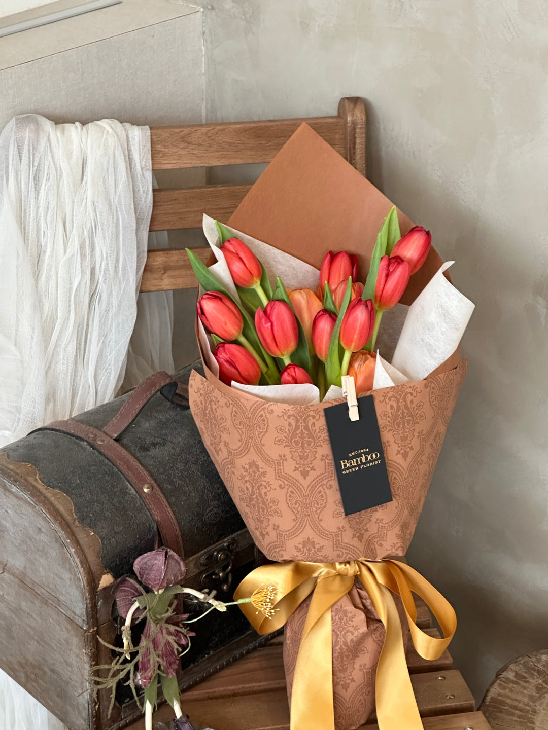 Red and orange tulips wrapped in brown paper, creating a vibrant and rustic floral arrangement. Premium tulips, elegant bouquet, rustic floral design, Penang florist.