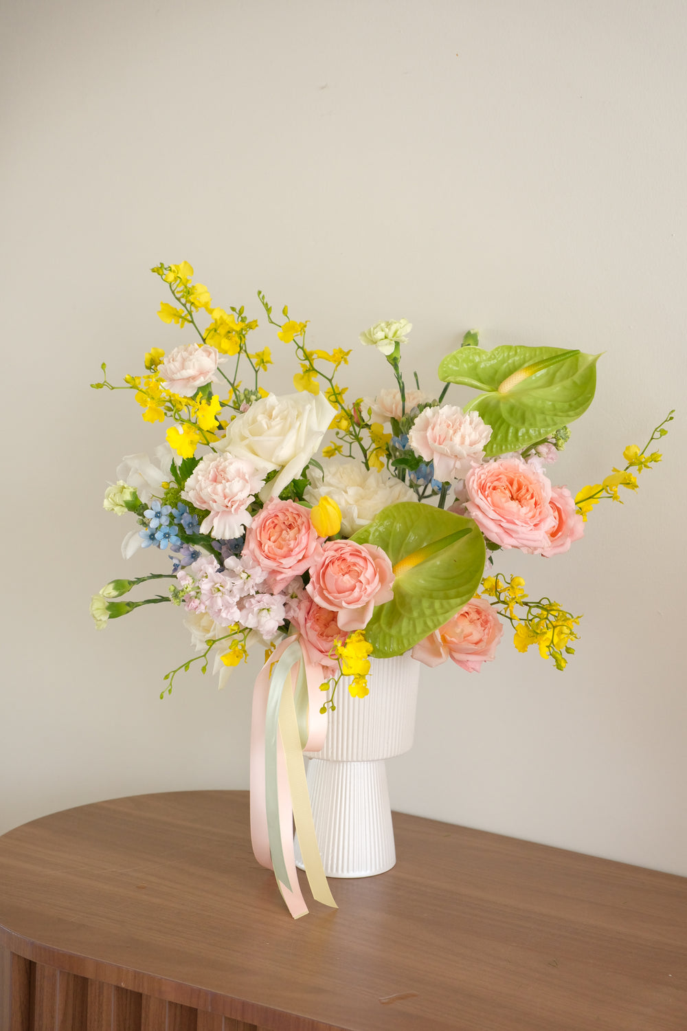 Modern Mother's Day garden-style flower arrangement with pink roses, green Anthuriums, and yellow Dancing Lady orchids in a white ribbed vase by Bamboo Green Florist