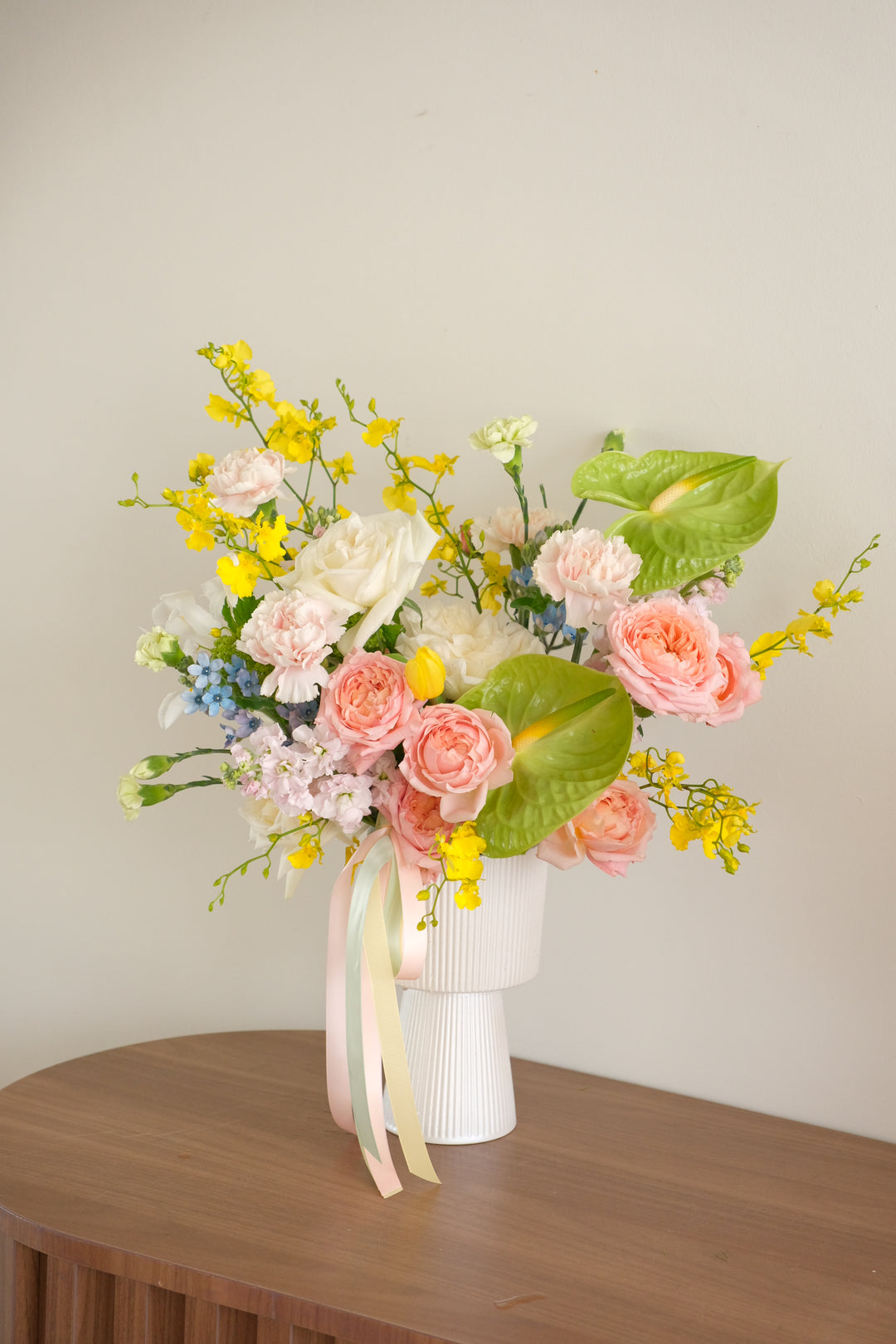 Modern Mother's Day garden-style flower arrangement with pink roses, green Anthuriums, and yellow Dancing Lady orchids in a white ribbed vase by Bamboo Green Florist