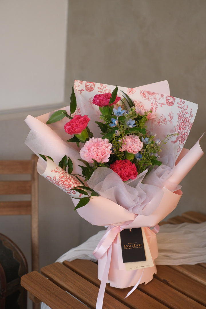 An elegant bouquet of assorted flowers, including carnations, roses, and lilies, arranged in a vase. The vibrant colors and delicate blooms convey love, gratitude, and appreciation for mothers and mother figures."