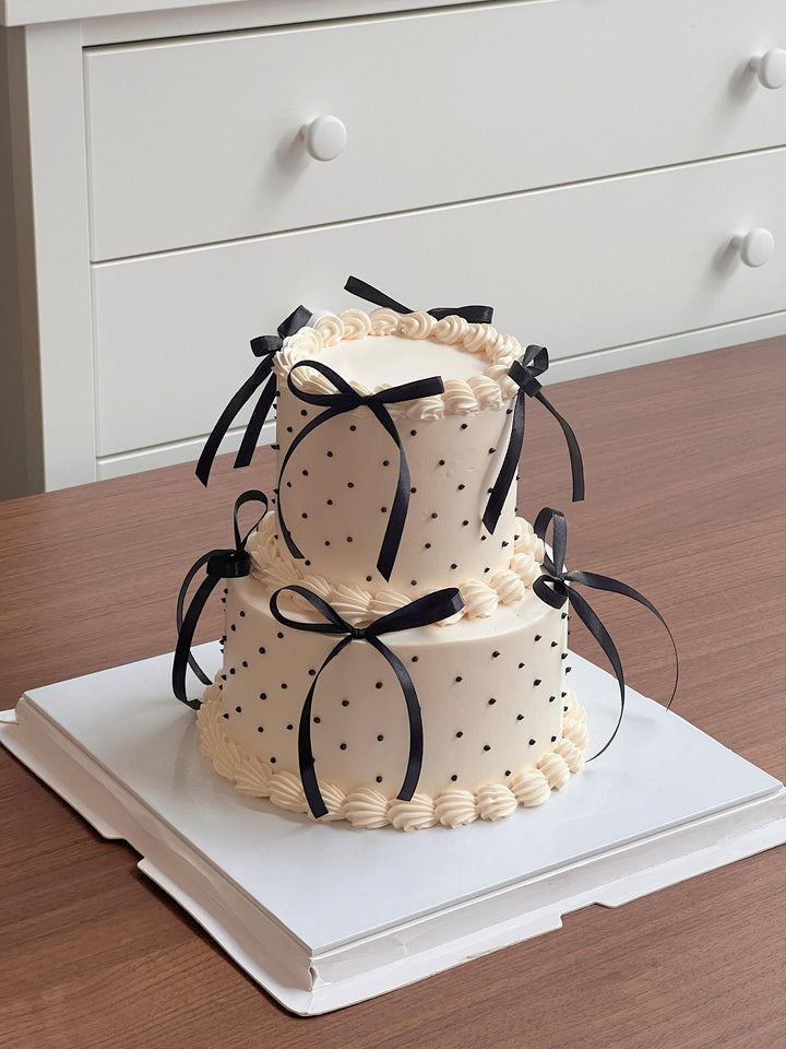 Two-tier fresh cream cake with black satin bows and hand-piped dots, by Bamboo Green Florist, the No.1 online florist in Penang