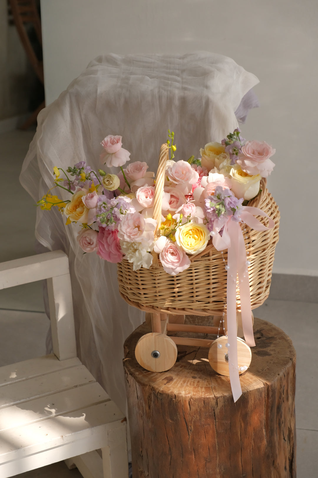 First Light flower basket styled on a wooden stand, a keepsake pram gift for a new mother, delivered across Penang.

