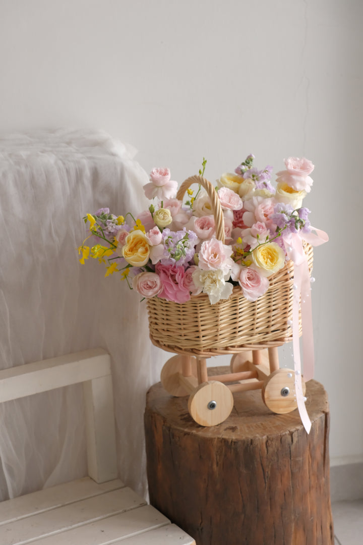 Close-up of the garden roses, lavender stock and soft yellow blooms in the First Light new mother flower basket.
