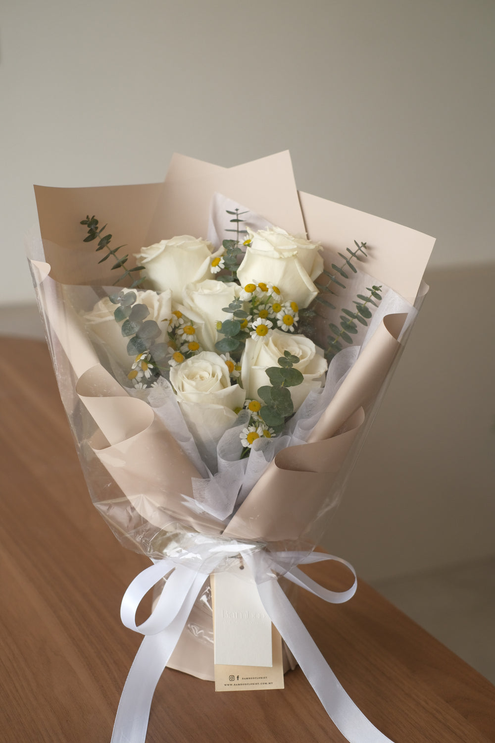 bouquet of white roses and chamomiile in brown wrap