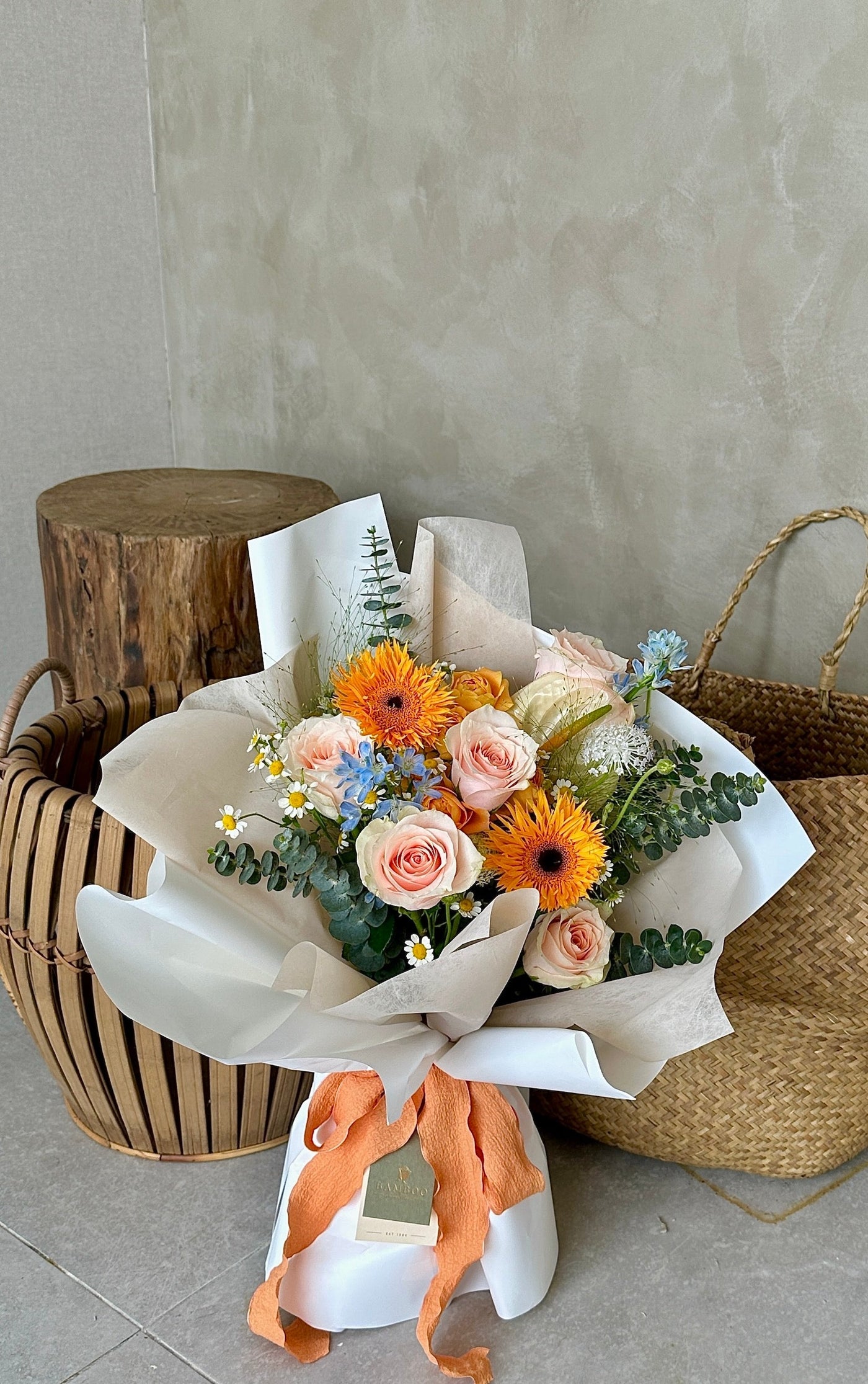 "Toasting to the woman who taught me everything I know about making the perfect slice of toast. Happy Mother's Day!"   Celebrate the magic mom-ents with this mixed bouquet features orange daisies, orange rose spray,  peach roses, seasonal fillers in a warm hues.   Standard: 10 main flowers + fillers , bouquet height approximate 40cm  Wowsome: 20 main flowers + fillers , bouquet height approximate 50cm