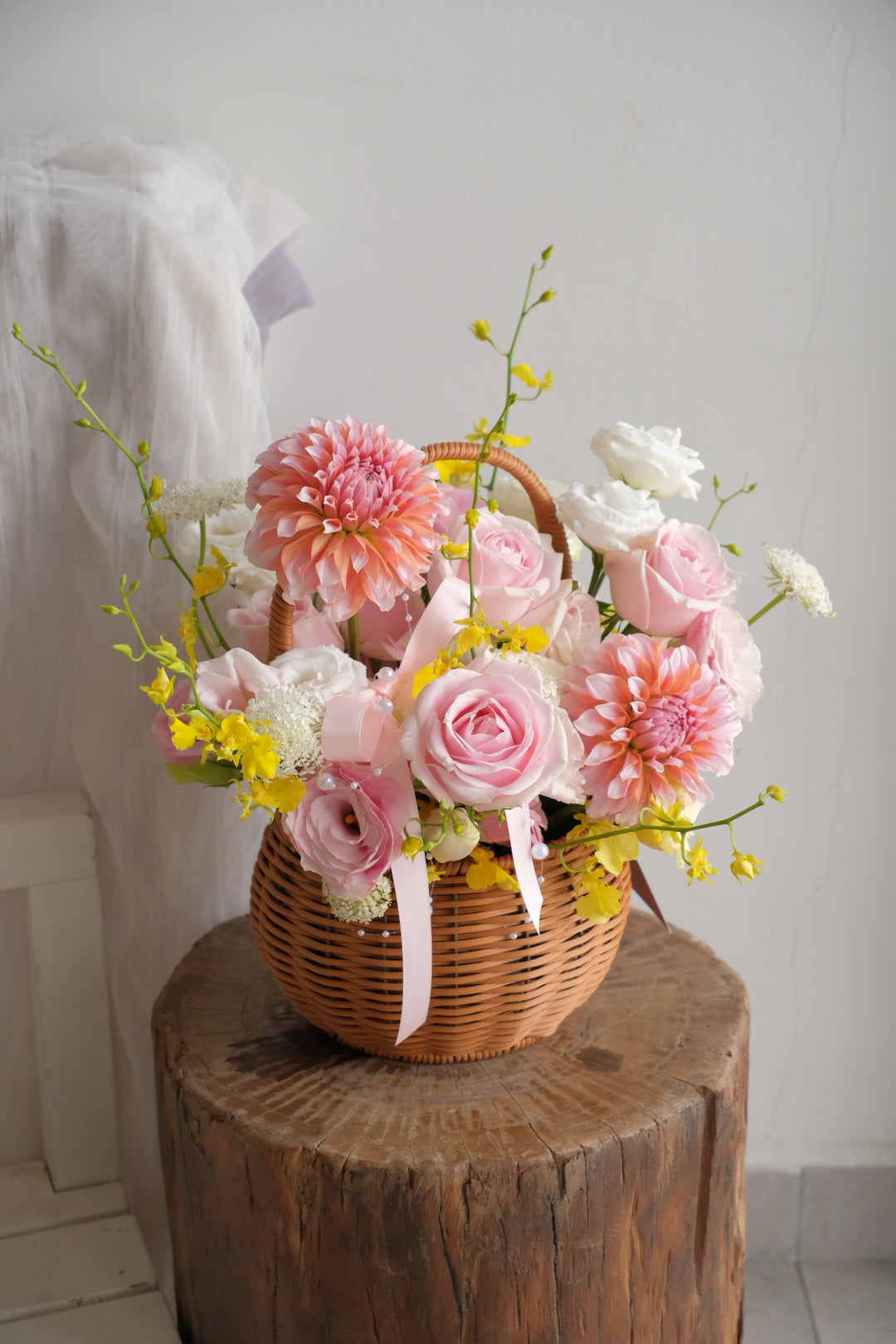 Columbia garden flower basket with blush roses, peach dahlias, yellow oncidium and white lisianthus in a hand-woven handled basket.