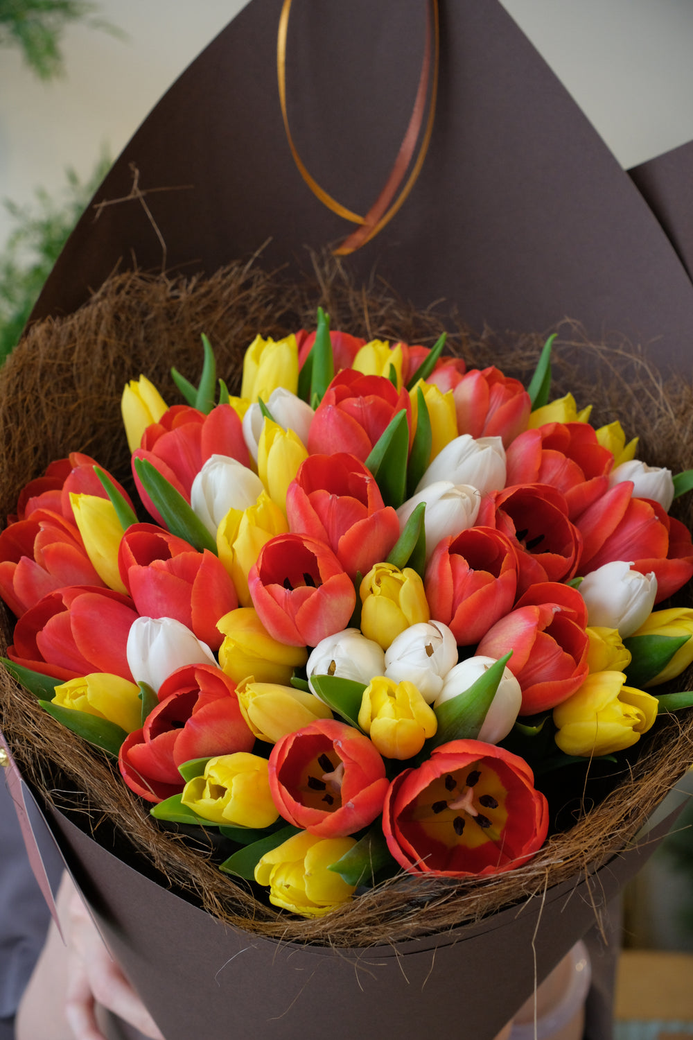 Bouquet of red, yellow, and white tulips in a brown paper wrap.