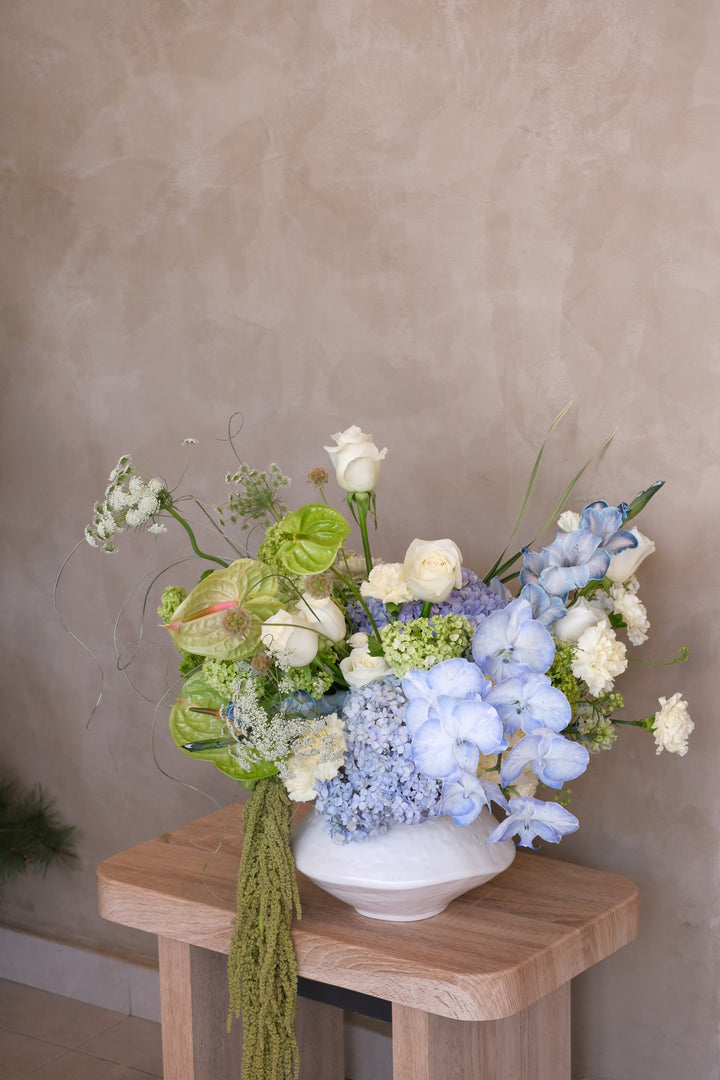 Omakase Serene blue and white flower arrangement — hydrangea, orchids and white roses in a handmade white ceramic pot by Bamboo Green Florist

