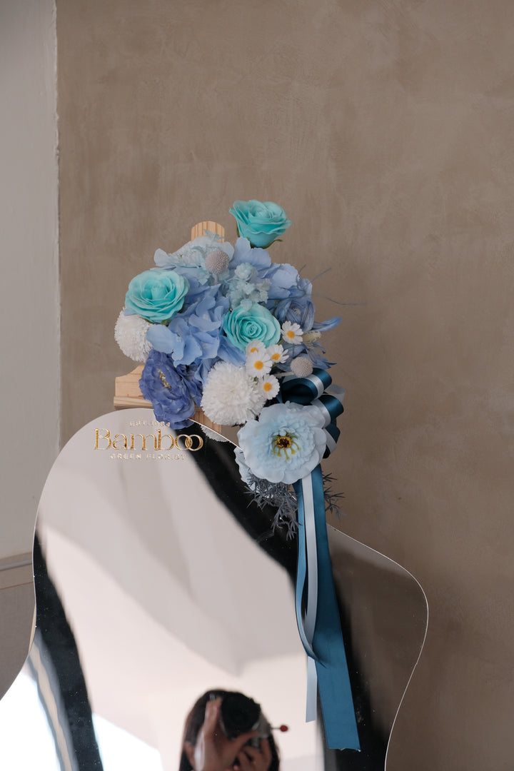 Ophelia Acrylic Mirror featuring a handcrafted blue-themed artificial floral arrangement with elegant ribbons, customizable message panel, and wooden display rack. Perfect for events, gifting, and tabletop decoration.