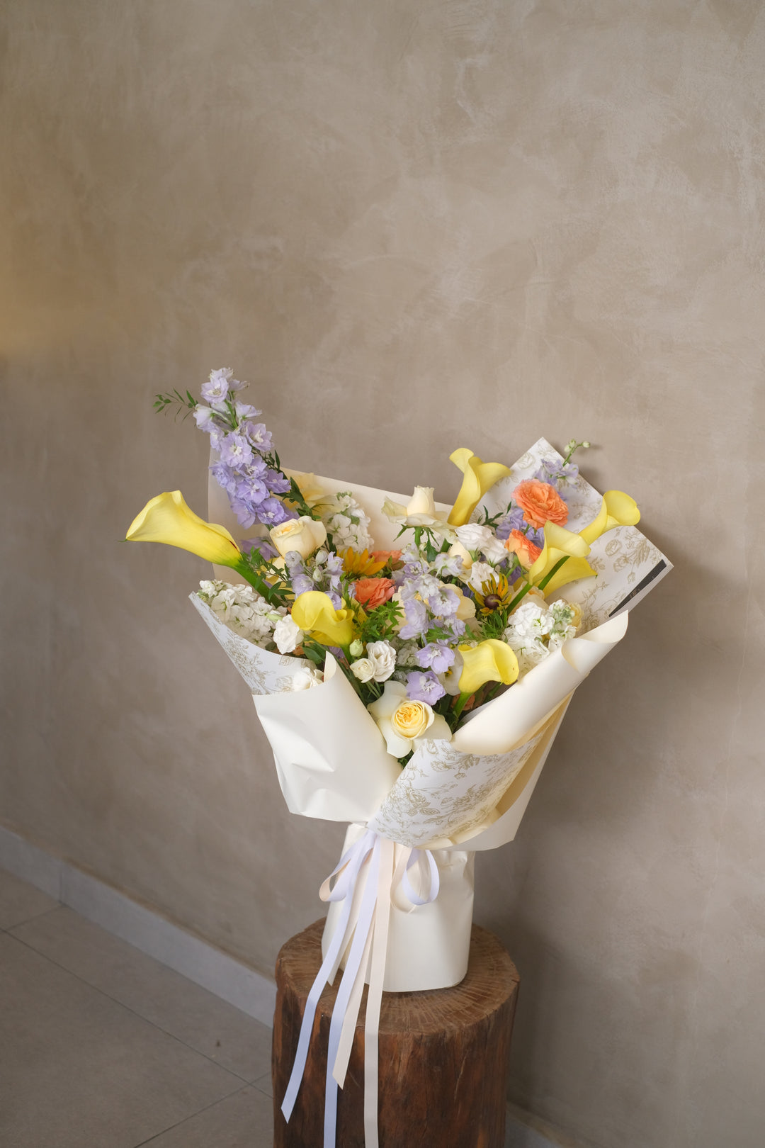 An enchanting floral masterpiece showcasing radiant yellow calla lilies intertwined with exquisite yellow roses, forming a vibrant display of freshness and joy. This stunning arrangement emanates warmth and cheer, ideal as a centerpiece for celebrations or an unforgettable gift. Its elegance and beauty promise to illuminate any space with a touch of sunny delight