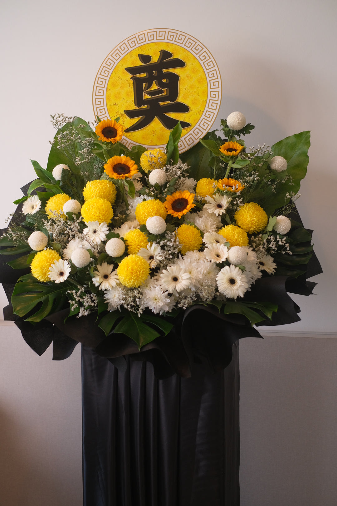 To offer heartfelt condolences during a time of loss, this arrangement combines vibrant sunflowers, delicate white daisies, cheerful gerbera daisies, ping pong flowers, chrysanthemums, soft pompoms, and lush ferns. Each bloom reflects the joy and beauty your loved one brought to life, creating a touching tribute to honor their memory.