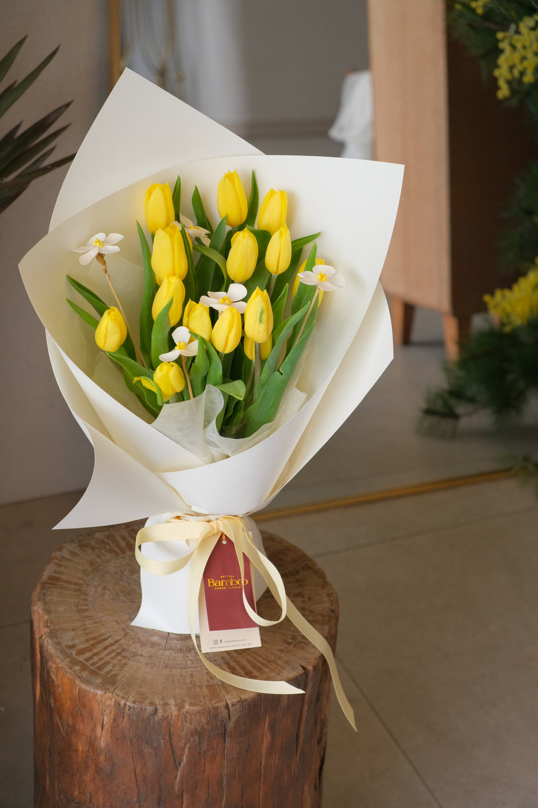 Bouquet of yellow tulips wrapped in white paper.