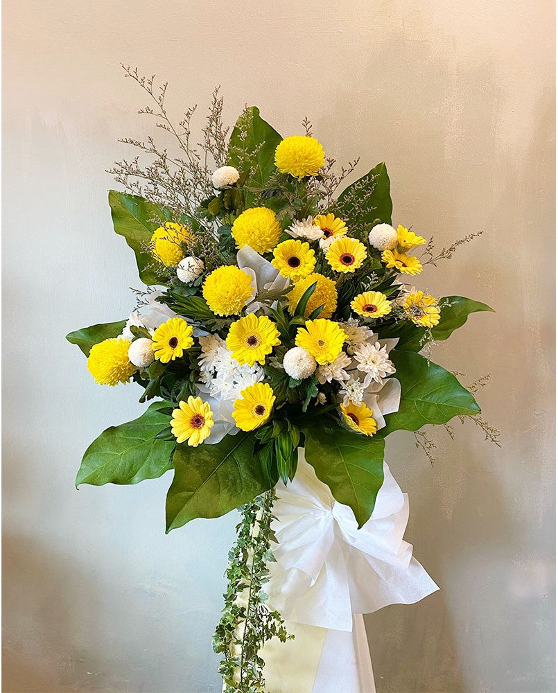 An expression of love, empathy and remembrance, this is a lovely funeral flower choice for those who lived life to the full. Designed to bring a touch of light to the very darkest of days, it includes an uplifting arrangement of yellow gerberas, yellow ping pongs, pompoms in decorative greens. For same day condolences flowers delivery in Butterworth.