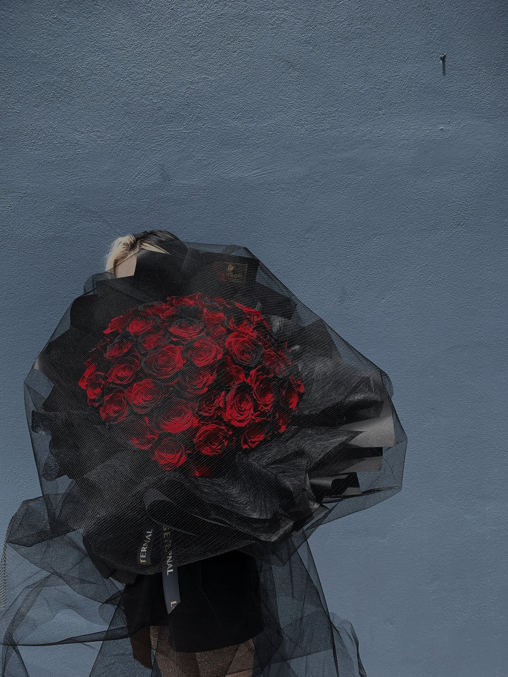 luxurious red roses with a hint of black in each stalks mysteriously present in black wrap & hovers with a soft layers of net.