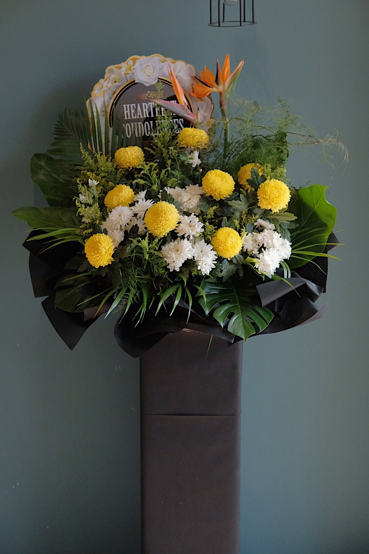 This beautiful, yellow Chrysanthemums, Bird of Paradise and soothing greens creates a peaceful presentation at any funeral or wake.   Note: Florals used and final design will vary depending on seasonality and availability.  For same day condolences flowers delivery in Butterworth